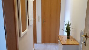 Un pasillo con puertas de madera, un espejo, una planta pequeña y un radiador.