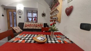 A cozy living room with a checkered tablecloth, a vase with flowers, and a heart-shaped decoration on the wall. - LA CANONICA nature and peace, with terrace Wi-Fi PetFriendly with dog area (Baselga di Piné)