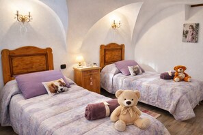 A bedroom with two beds, each with a headboard, a nightstand, a lamp, and a teddy bear.