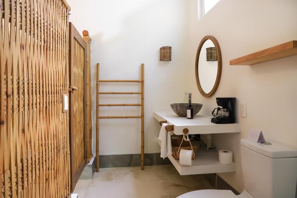 A bathroom with a bamboo door, a towel rack, a sink with a mirror, and a toilet.