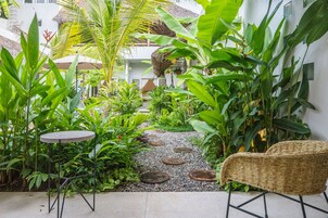 Un jardín con un sendero, una silla de mimbre y una pequeña mesa.