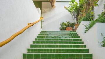 Eine Treppe mit grünen Fliesen, einem Holzgeländer und Blumentöpfen.
