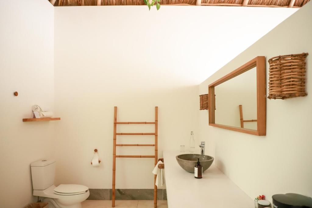 A bathroom with a toilet, a sink, a mirror, and a towel rack.
