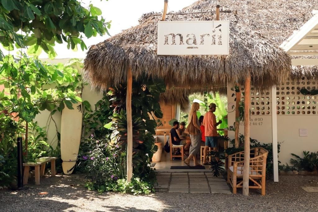 A thatched-roof outdoor seating area with a sign reading 'maría'.