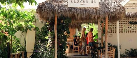 A thatched-roof outdoor seating area with a sign reading 'maría'.