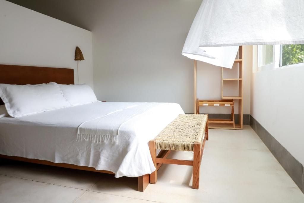 A bedroom with a bed, a bedside table, a chair, and a window with a view.
