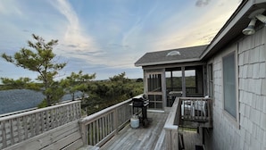 A wooden deck with a covered area, a grill, and a view of the surrounding landscape. - Charming Cottage, South Nags Head, 5 min walk to the beach (Nags Head)