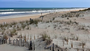 A sandy beach with dunes and a wooden fence. - Charming Cottage, South Nags Head, 5 min walk to the beach (Nags Head)