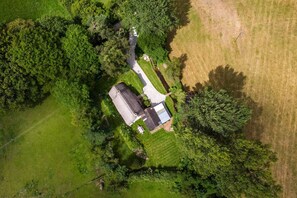 An aerial view of a property with a house, a driveway, and surrounding greenery. - Weeke Brook (Chagford)