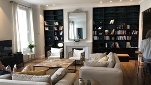 A modern living room with a fireplace, a large bookshelf, and a television.