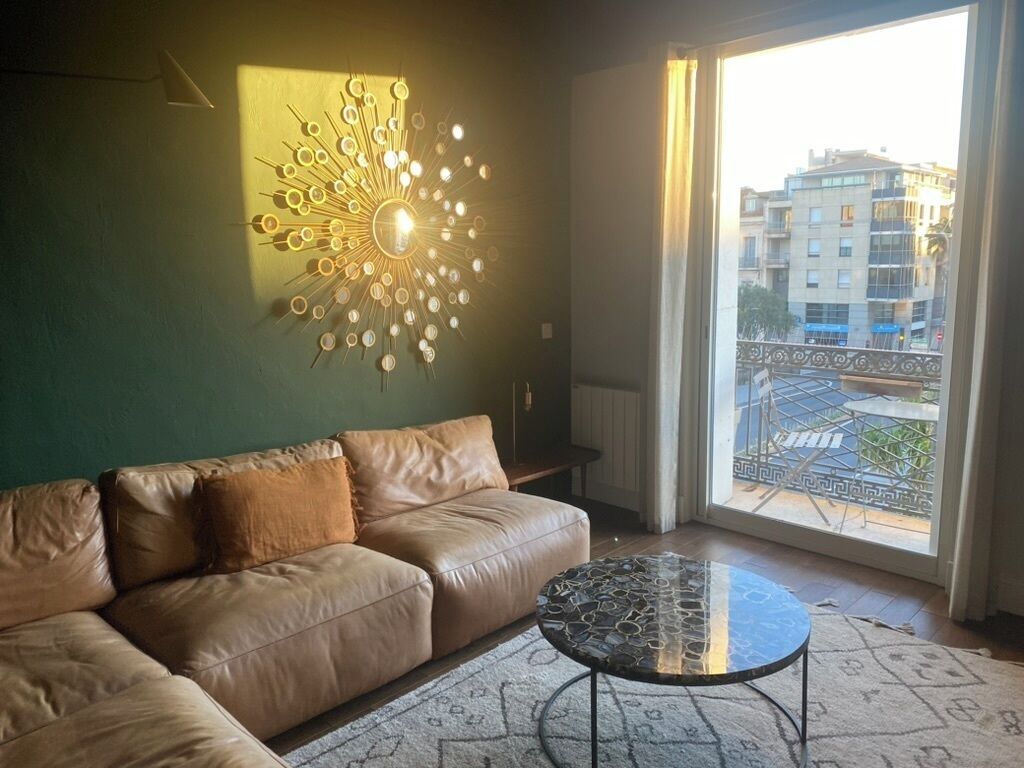 A living room with a leather sofa, a round coffee table, and a wall-mounted light fixture.