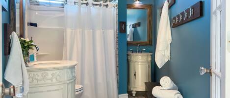 Et badeværelse med hvid kommode, badekar, toilet og vask.