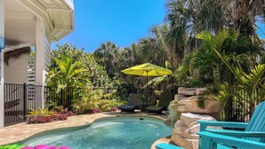 A clear swimming pool with lounge chairs and a tropical garden setting. - Tropical Oasis - Pool w/ Waterfall & Swing Bar (Captiva)