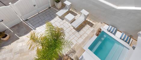 A rooftop pool area with a hot tub, lounge chairs, and a potted plant.