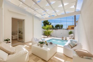 Ein moderner Außenbereich mit Pool, weißer Möbel und einer Pergola.