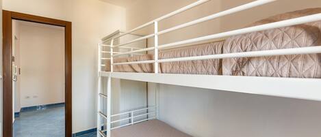 Habitación con literas, puerta de madera y suelo de baldosas azules.