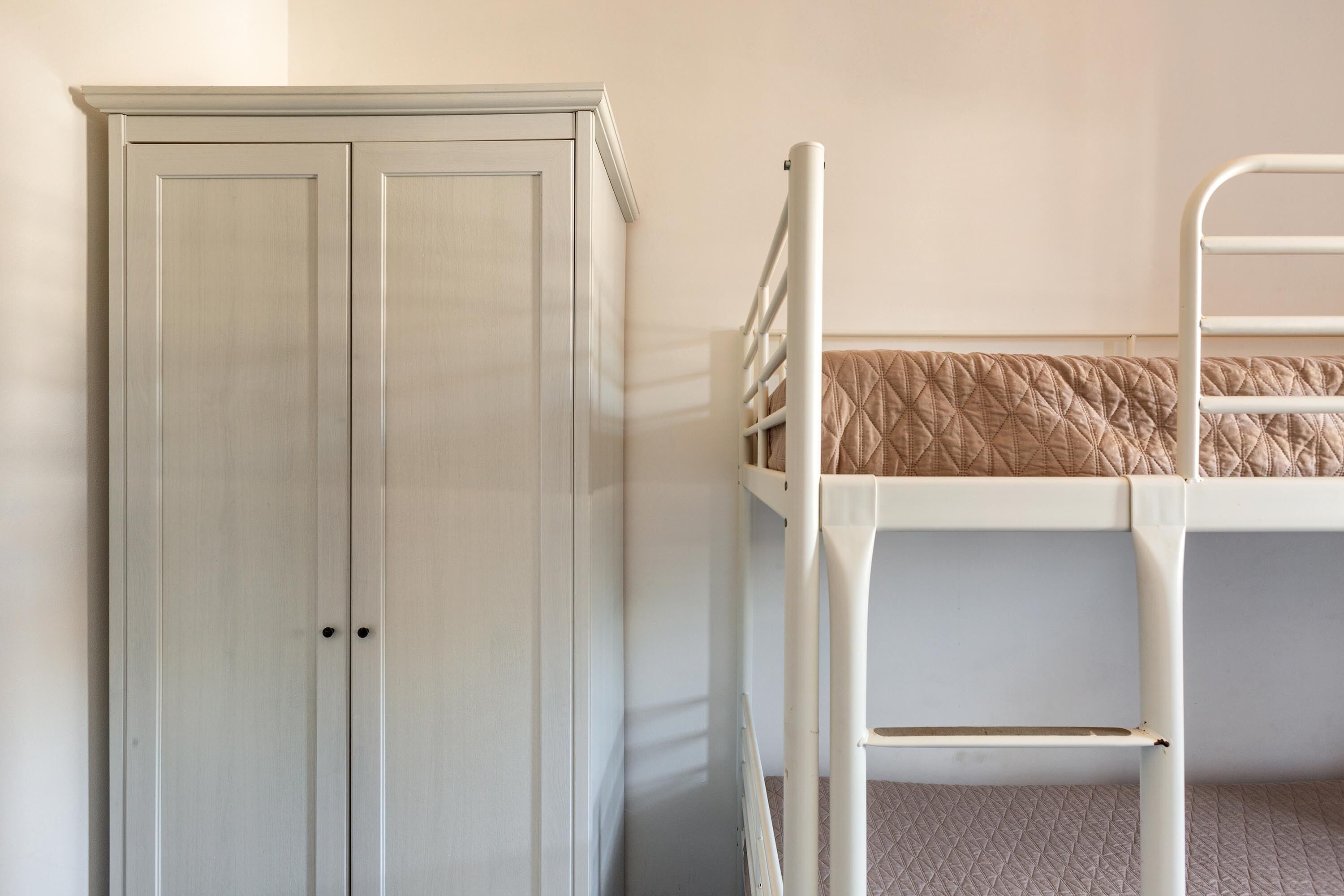 A bunk bed with a quilted mattress and a white metal ladder.