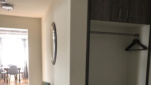 Een kamer met een garderobe, een klein bureau en een spiegel. Door een deuropening is een zithoek zichtbaar.