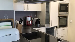 Een moderne keuken met een ingebouwde kookplaat, een koffiezetapparaat en een magnetron.