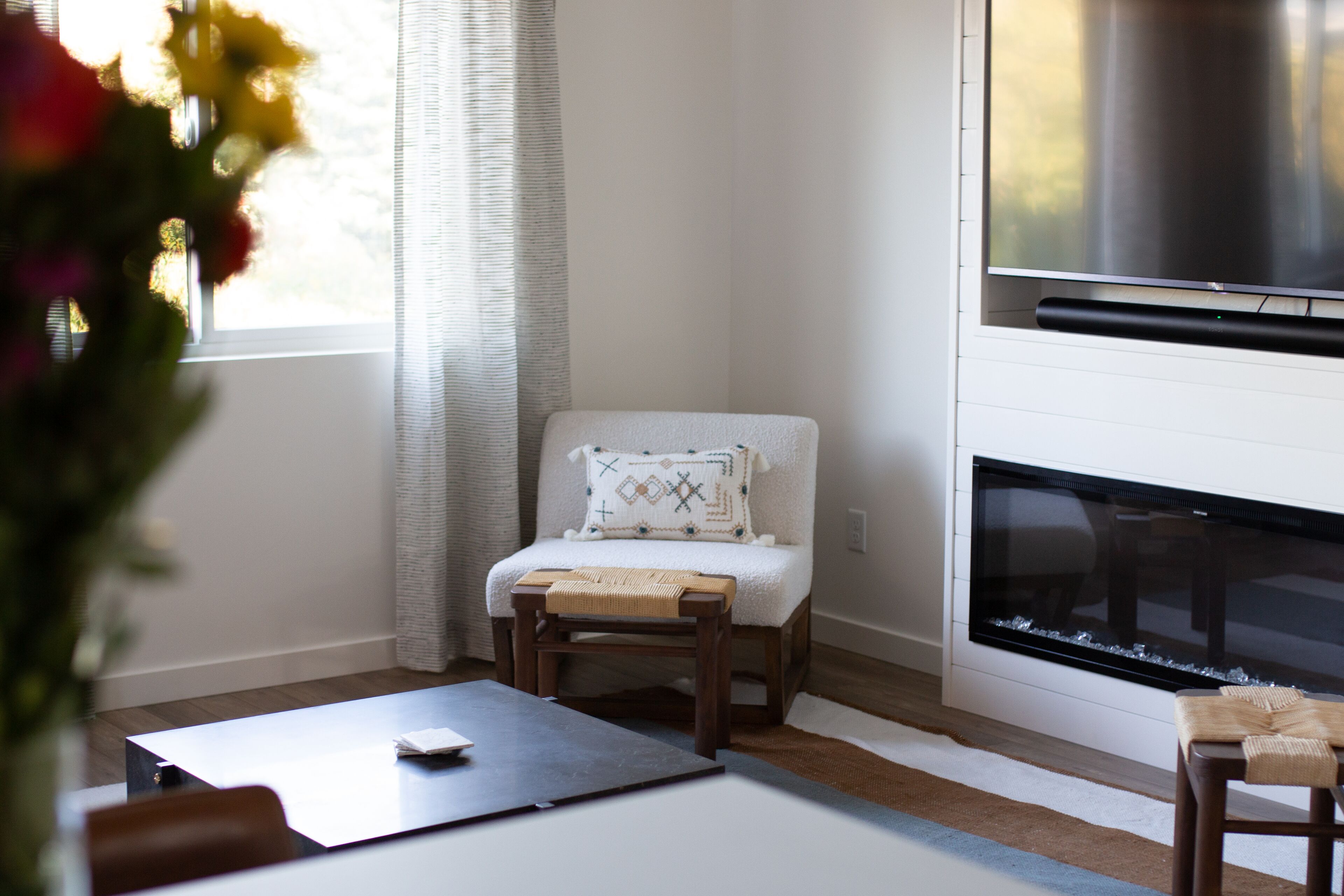 A living room with a fireplace, a white armchair, and a small wooden table.