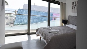 A hotel room with a large bed, a view of a modern building, and a sign reading "CANNES VOS SPEC". - 7 Croisette - Luxury Apartment 603 (Cannes)