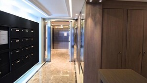 Un couloir bordé de casiers, avec un meuble en bois et un ascenseur.