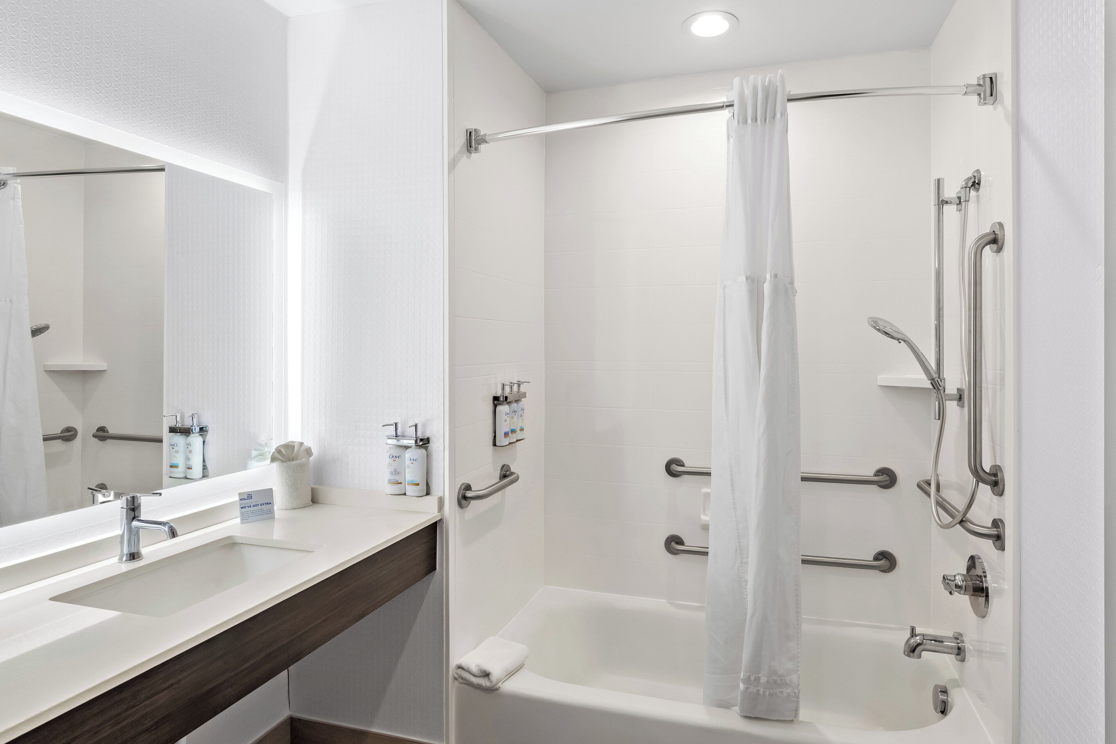 Une salle de bain moderne équipée d’une baignoire, d’une douche et d’un meuble-lavabo avec un miroir et des articles de toilette.
