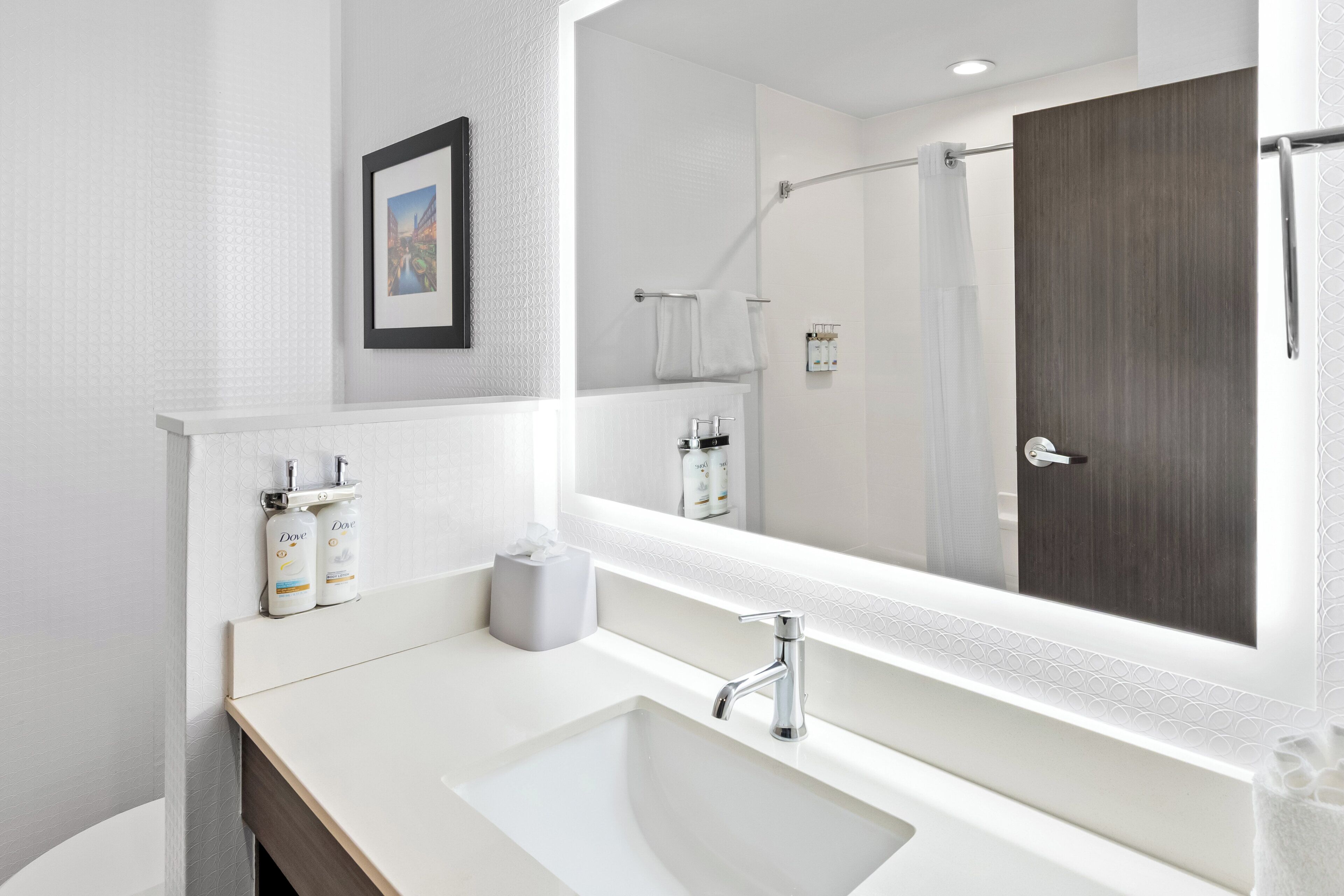A modern bathroom with a large mirror, a sink, and a shower area.
