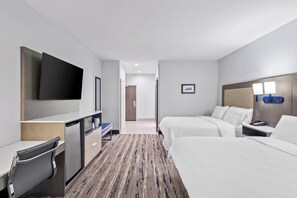 A hotel room with a bed, a desk, a TV, a bedside table, and a bathroom door.