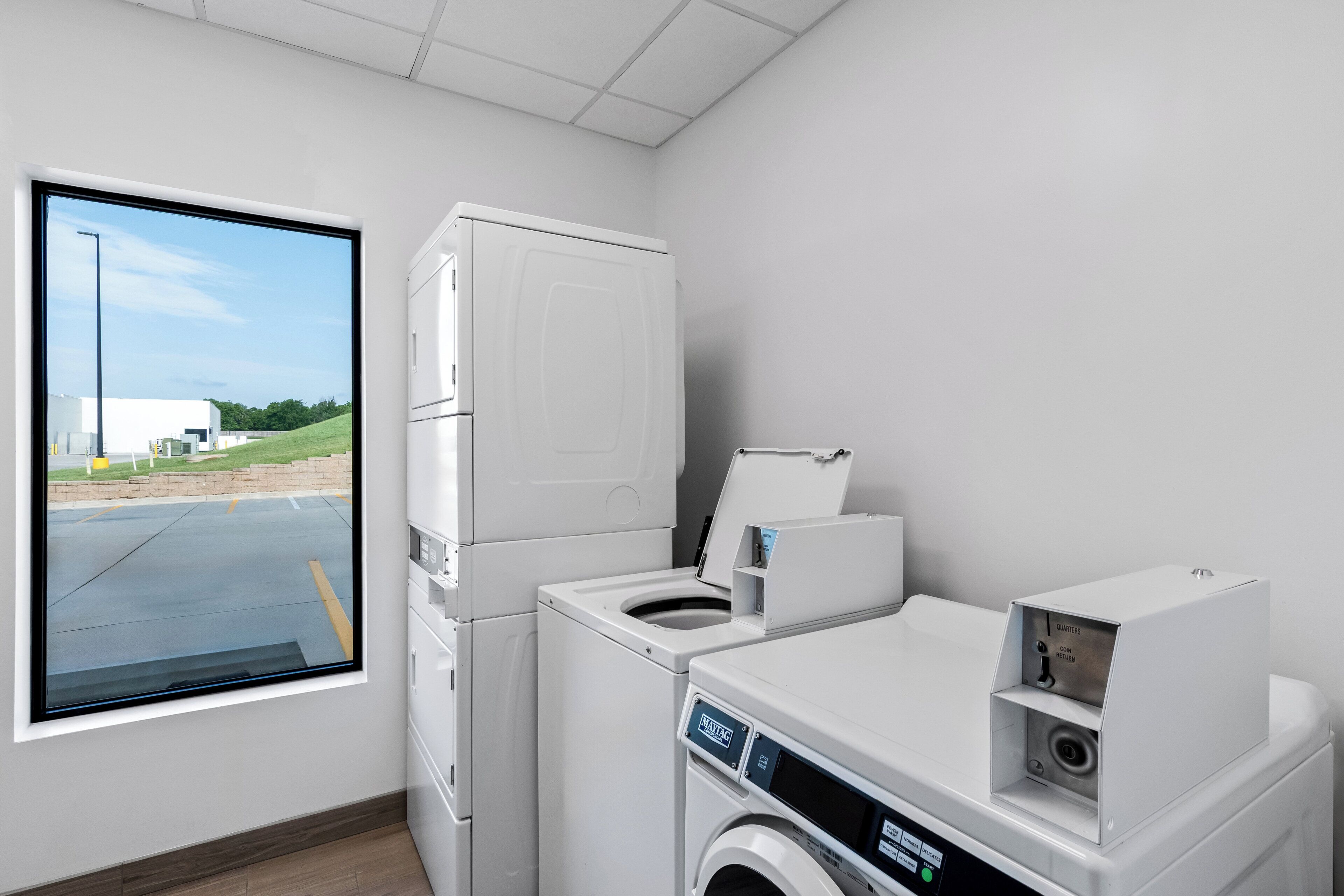 A laundry room with a large window, a washing machine, and a dryer.