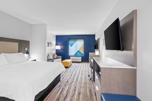 A hotel room with a large bed, a desk, a chair, a flat-screen TV, and a window with a view.