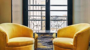 A room with two yellow armchairs facing a large window with a view of buildings. - Leprince Hotel Spa, BW Premier Collection (Le Mans)