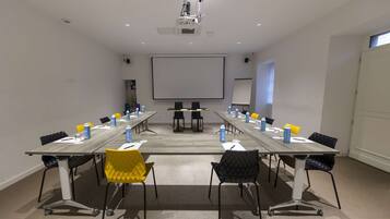 Ett konferensrum med ett långt bord, stolar, en projektor och en skärm.