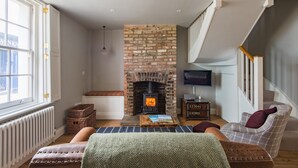 A cozy living room with a brick fireplace, a comfortable sofa, a television, and a bookshelf.