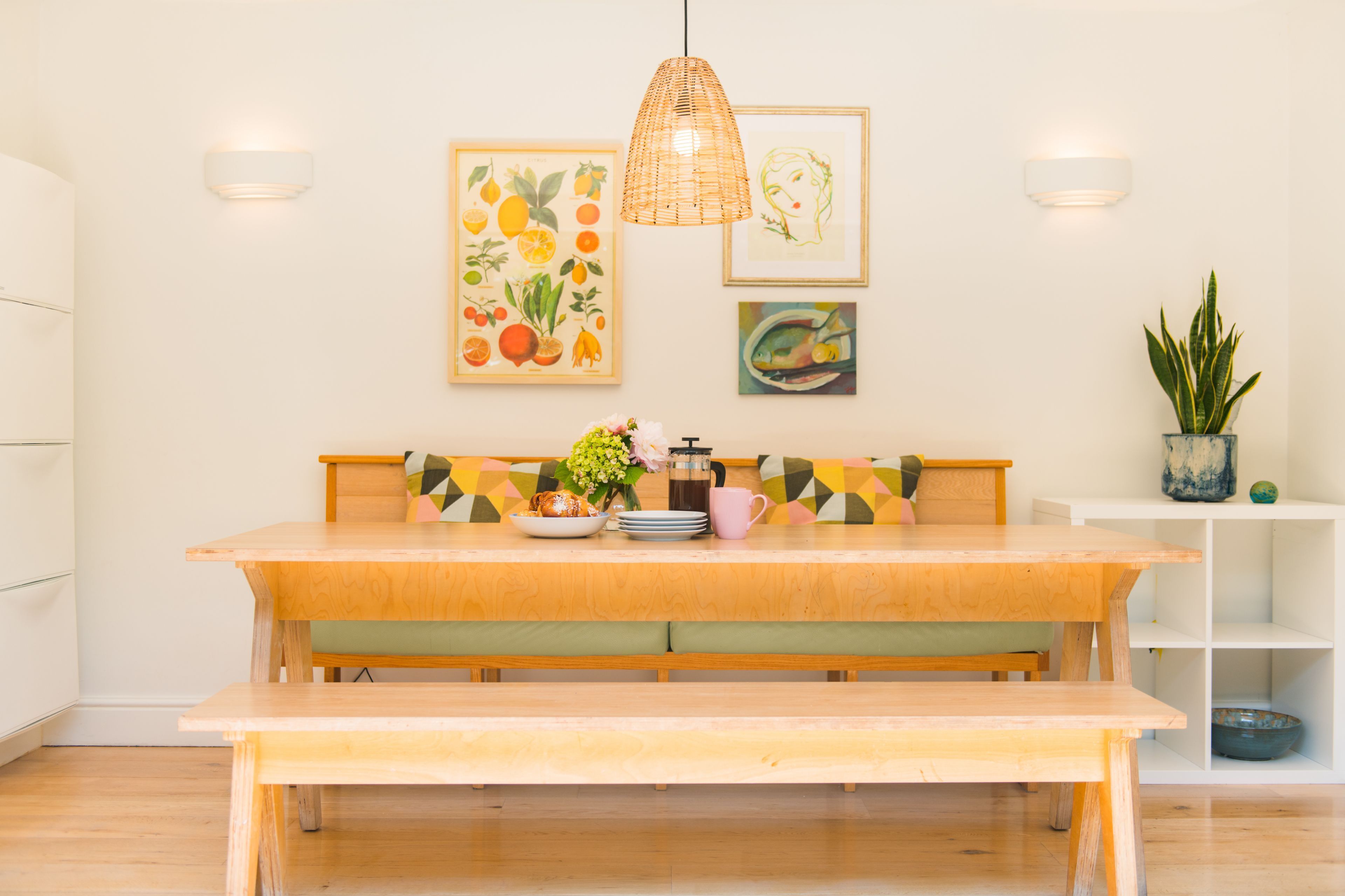 A wooden dining table with benches, a hanging light fixture, and wall art.