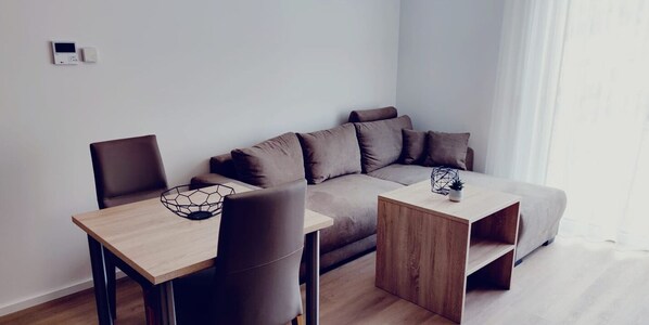 Een moderne woonkamer met een bank, twee stoelen, een salontafel en een bijzettafeltje.