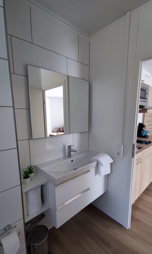 Een moderne badkamer met een grote spiegel, een witte wastafel en een handdoek aan de muur.