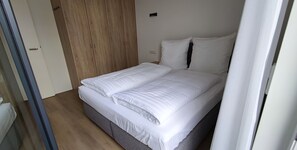 Een slaapkamer met een bed, een houten garderobe en een witte deur.