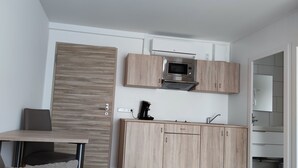 A modern kitchen with a built-in microwave, wooden cabinets, and a coffee machine. - Smart & Stay Aparthotel (Saarlouis)