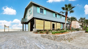 A two-story building with a balcony, a stone retaining wall, and a paved walkway. - La Anahi - Oceanfront Vacation Rental (St. Augustine)