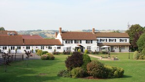 A white building with a tiled roof, a garden with a fountain, and outdoor seating. - Batch Country House (Weston-super-Mare)