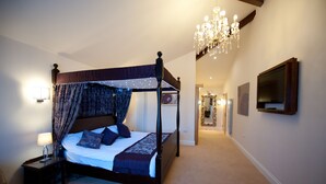 A four-poster bed with a canopy, a chandelier, a bedside lamp, and a television on the wall. - Batch Country House (Weston-super-Mare)