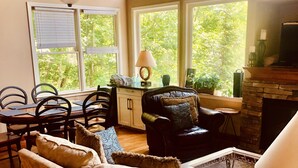 A cozy living room with a fireplace, comfortable seating, and large windows offering a view of greenery. - Chalet Suzanne of Helen (Helen)
