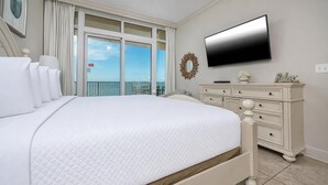 Une chambre avec un grand lit, une commode, un téléviseur à écran plat et une vue sur le ciel par la fenêtre.