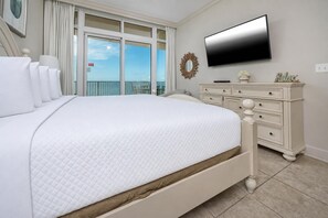 Un dormitorio con una cama grande, un aparador, un televisor de pantalla plana y vistas al cielo a través de la ventana.