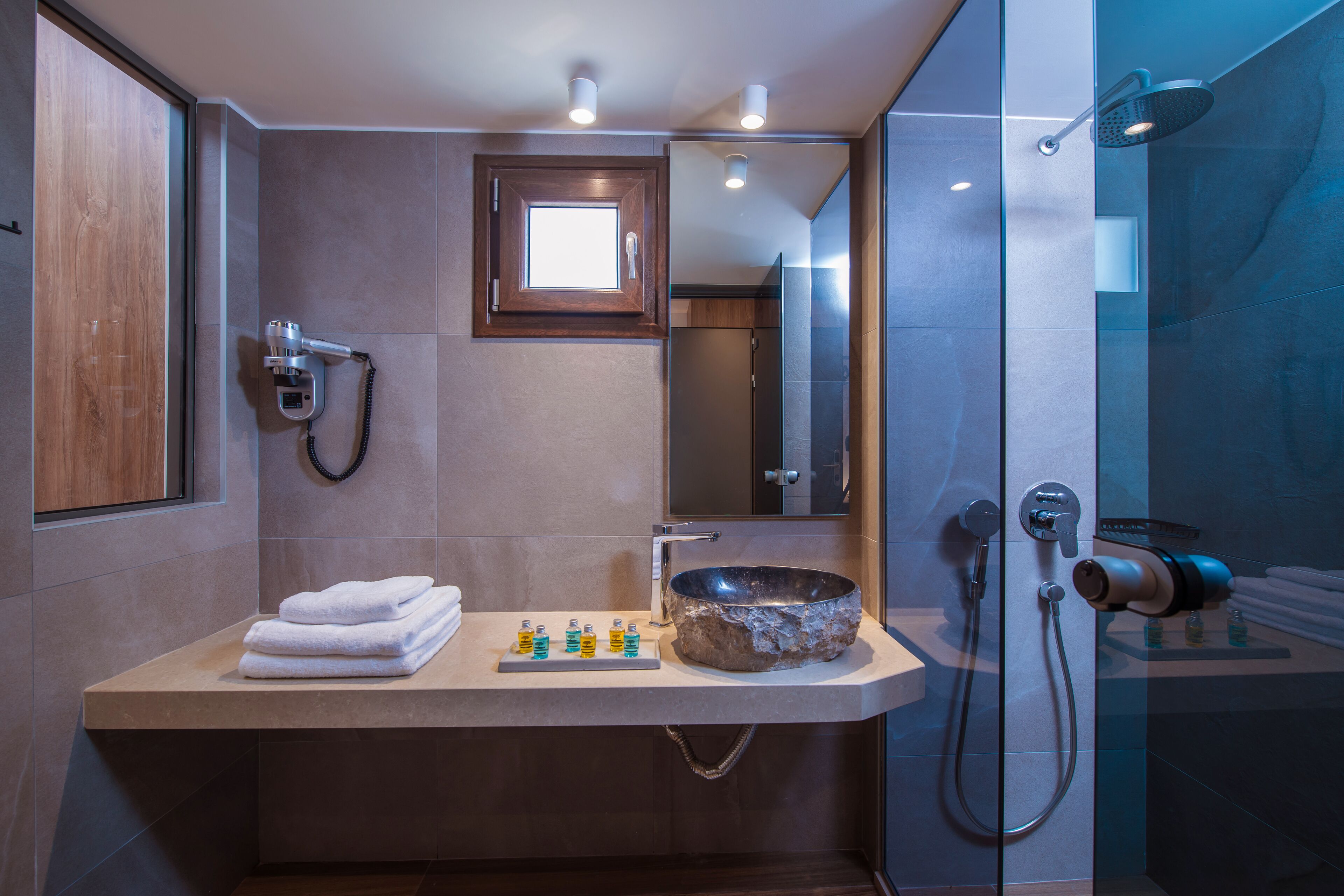 A modern bathroom with a large mirror, a built-in sink, and a shower area.