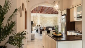 Une cuisine moderne dotée d’un îlot central, de murs en pierre et d’un plafond en bois.