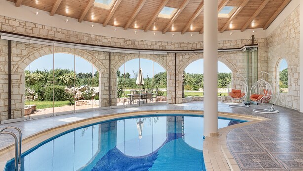 Une piscine agrémentée d’arches en pierre et offrant une vue sur la verdure.