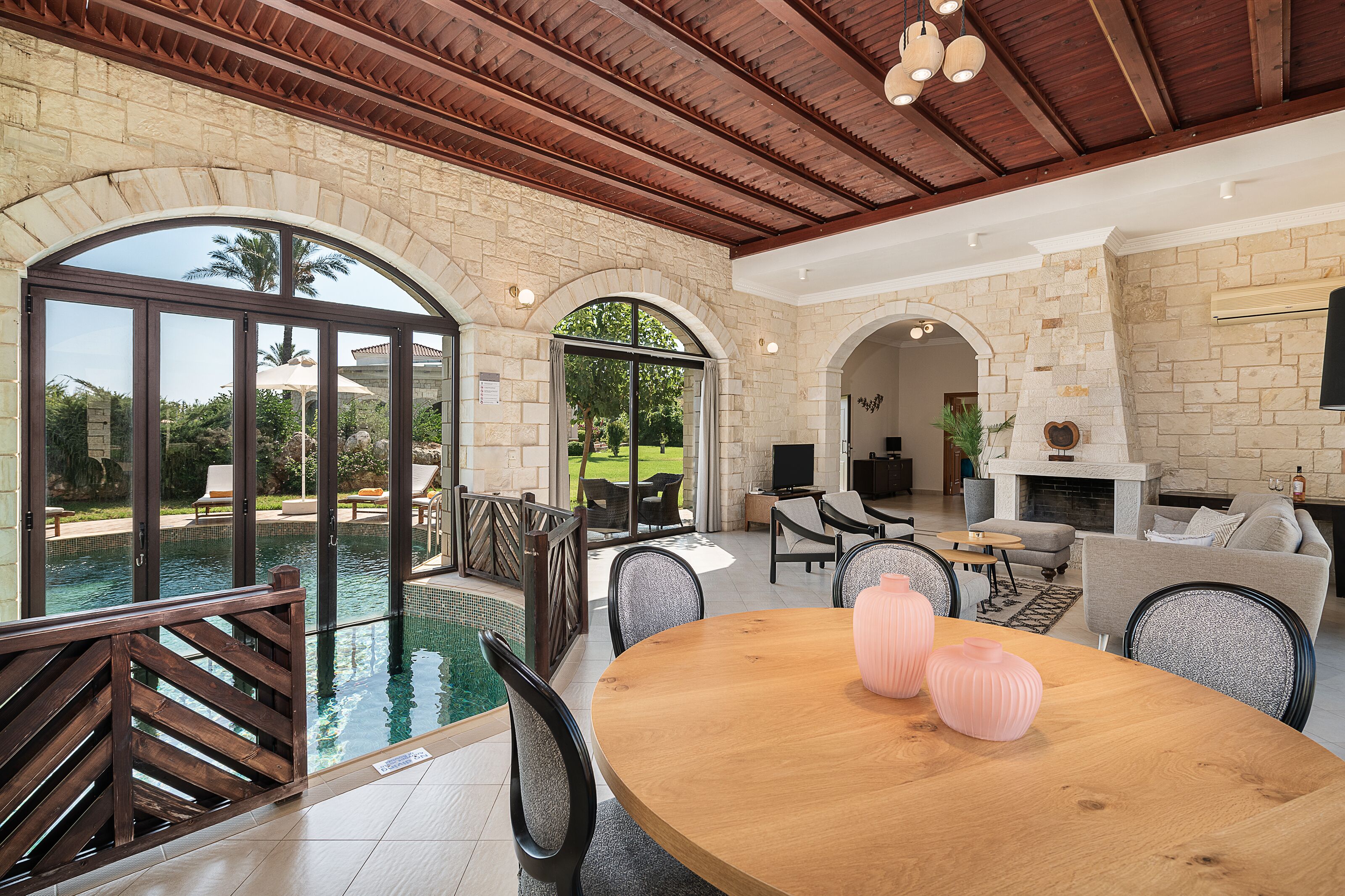 A spacious indoor area with a pool, a wooden dining table, and comfortable seating.