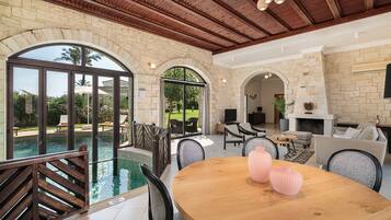 A spacious indoor area with a pool, a wooden dining table, and comfortable seating.